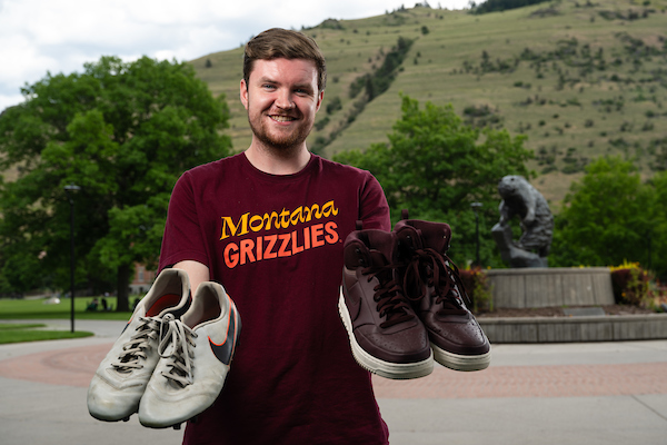 Sam Jones holds a pair of shoes in each hand and smiles