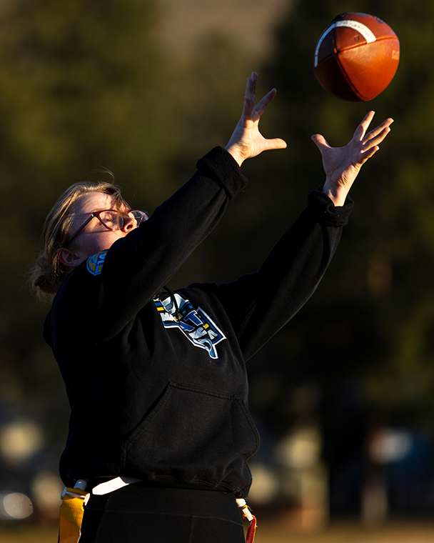 A flag football athlete reaches to secure a catch during practice