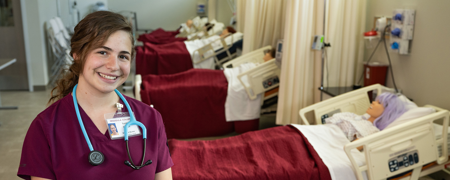 Successful Dual Enrollment student poses for photo in nursing lab classroom.