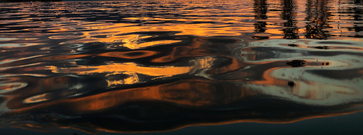 Ripples move across the top of Flathead Lake as it reflects an orange sunset