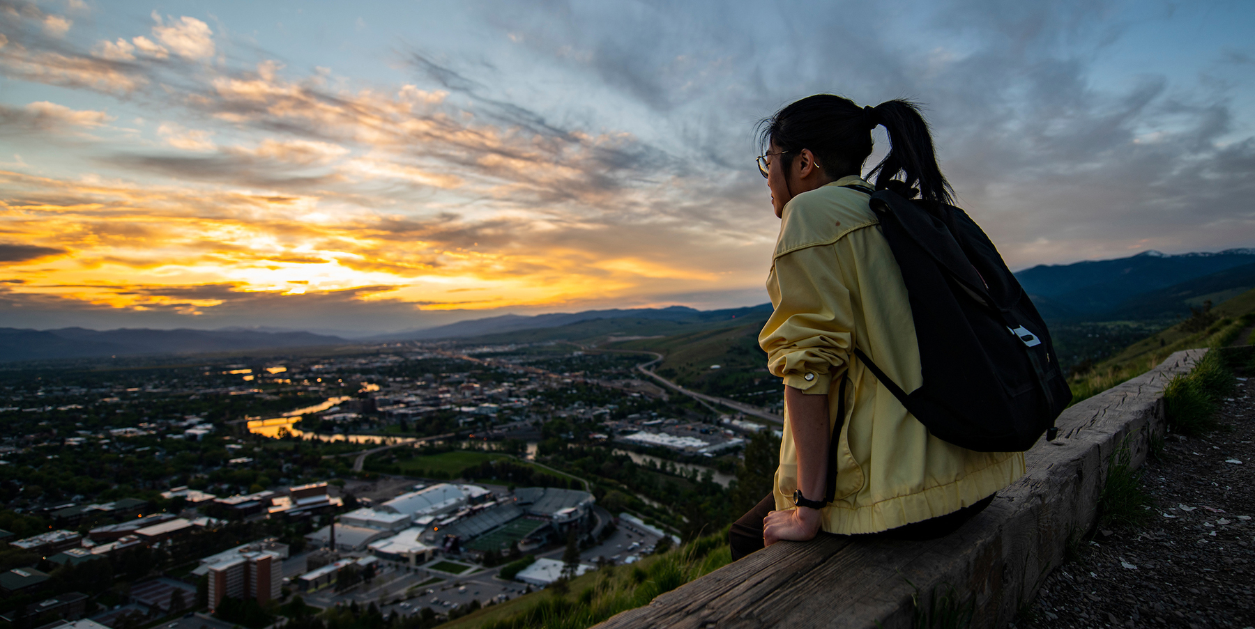 A student takes in a colorful sunset from the M on Mount Sentinel