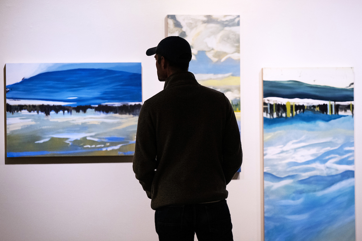 A person takes in student art work displayed in the Gallery of Visual Arts