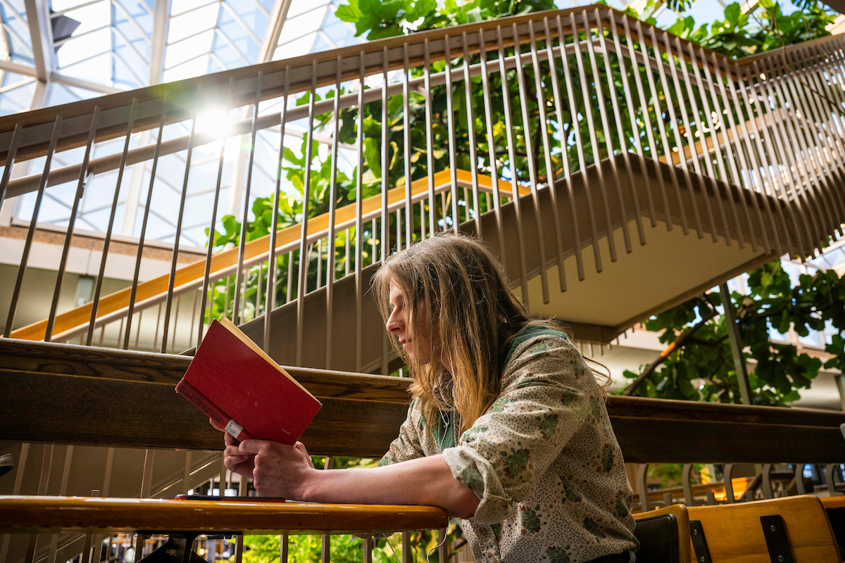 A student reads a hardback book in the University Center.